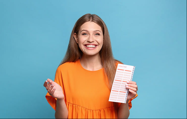A woman holding a lottery ticket and smiling.